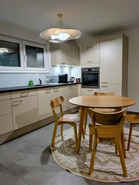 Cuisine blanche et bois avec table ronde, rangements intégrés et ambiance épurée aménagée par Melvi Intérieur