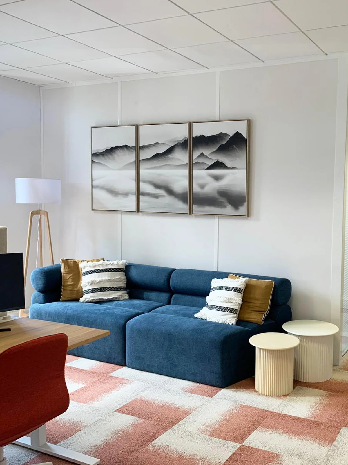 Espace détente de bureau professionnel avec canapé bleu, tapis graphique et décoration murale