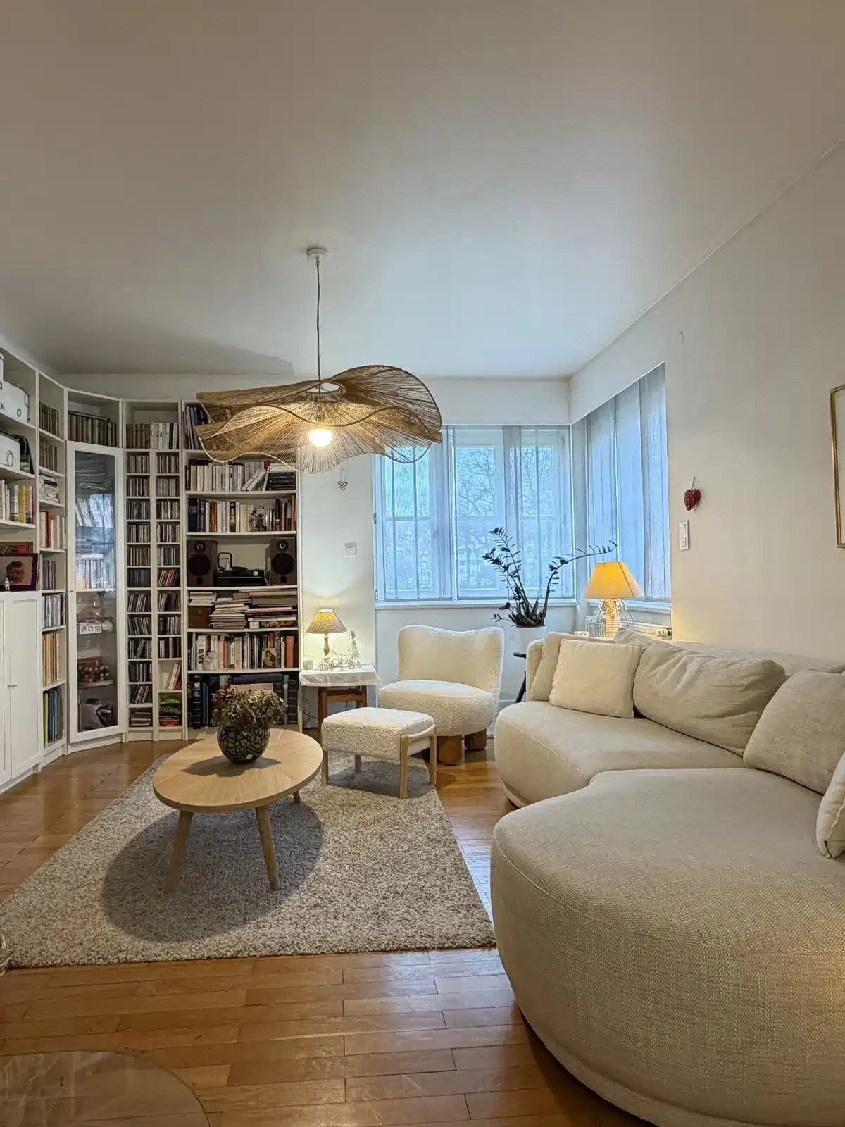 Salon rénové à l’ambiance chaleureuse avec canapé arrondi, table basse et bibliothèque sur mesure